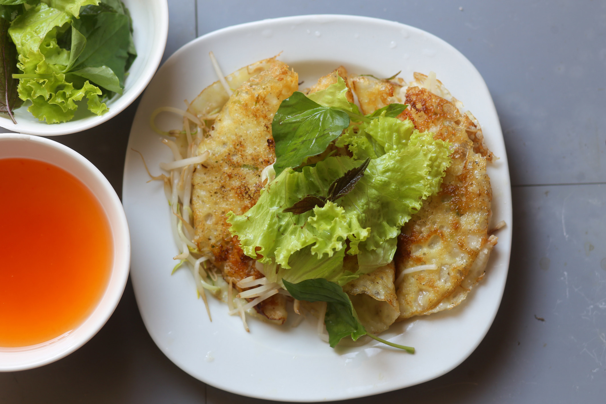 Close-up of crispy Vietnamese egg crêpe with vegetable and fish sauce.