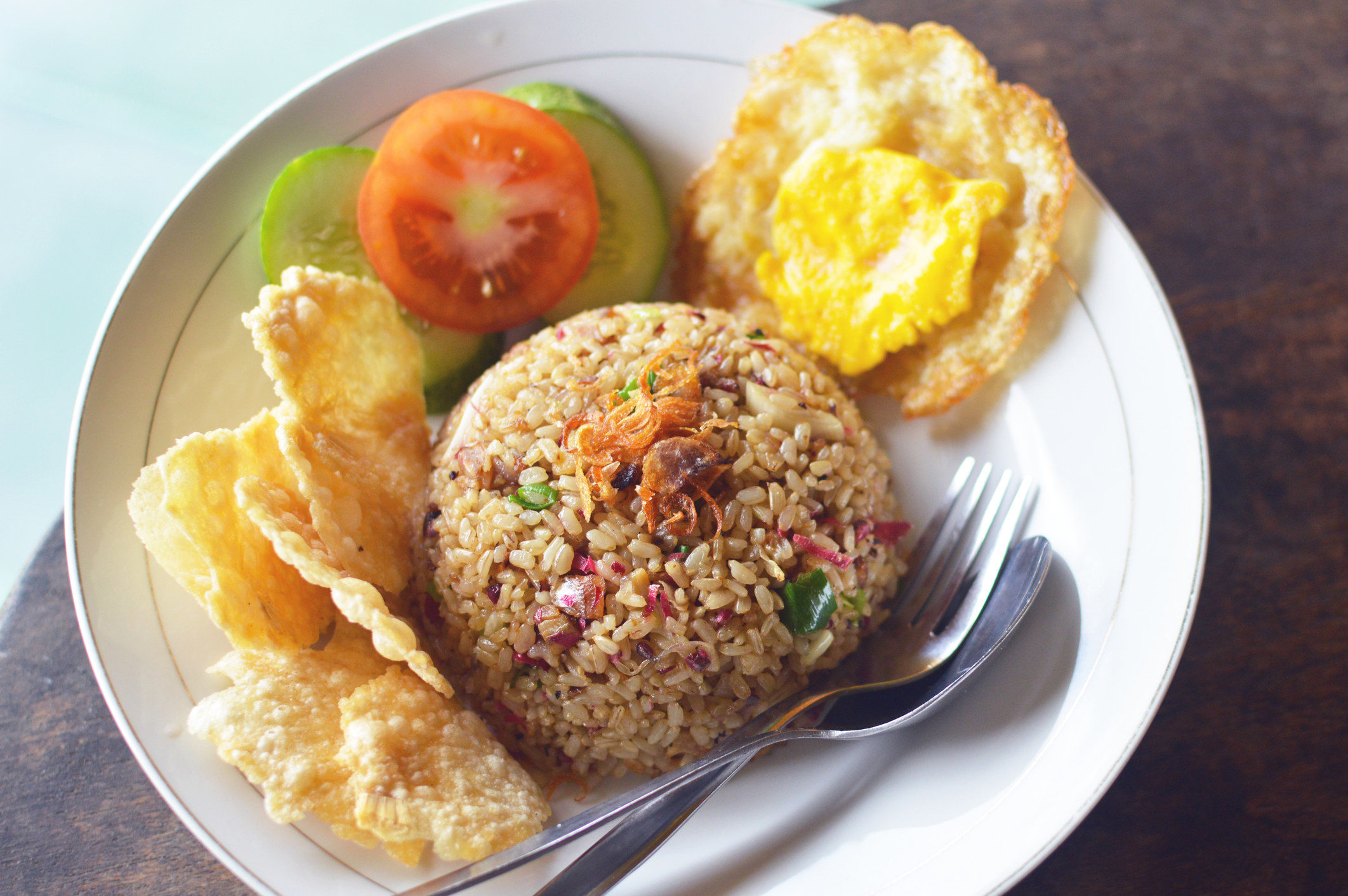 Fried Rice with a side of crackers, tomato, cucumber, and egg.