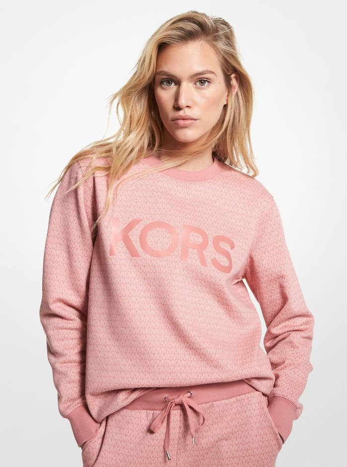 a person wearing a slouchy sweatshirt with the michael kors logo on the front