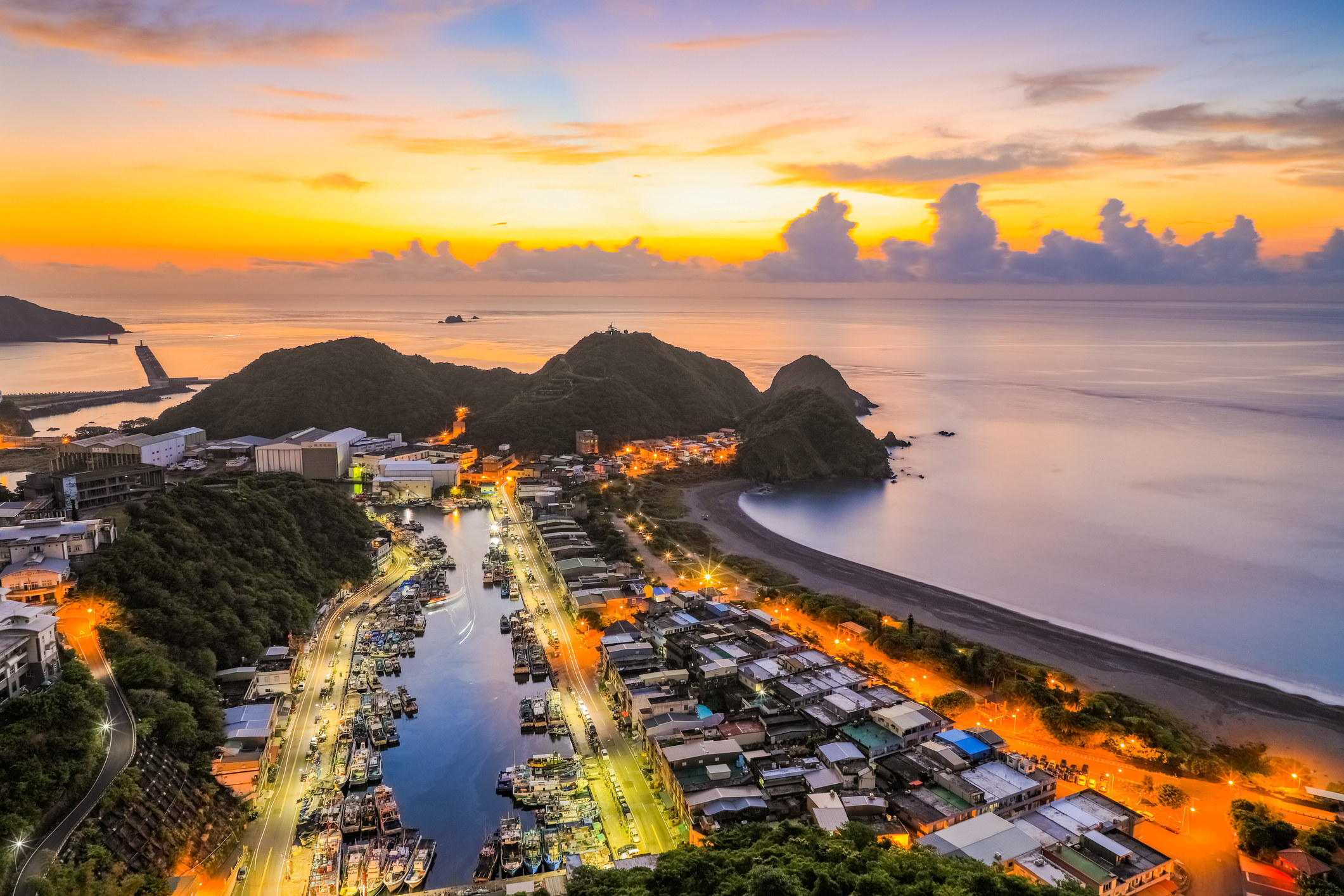 A view of a road and buildings against the sea and sky at sunset.