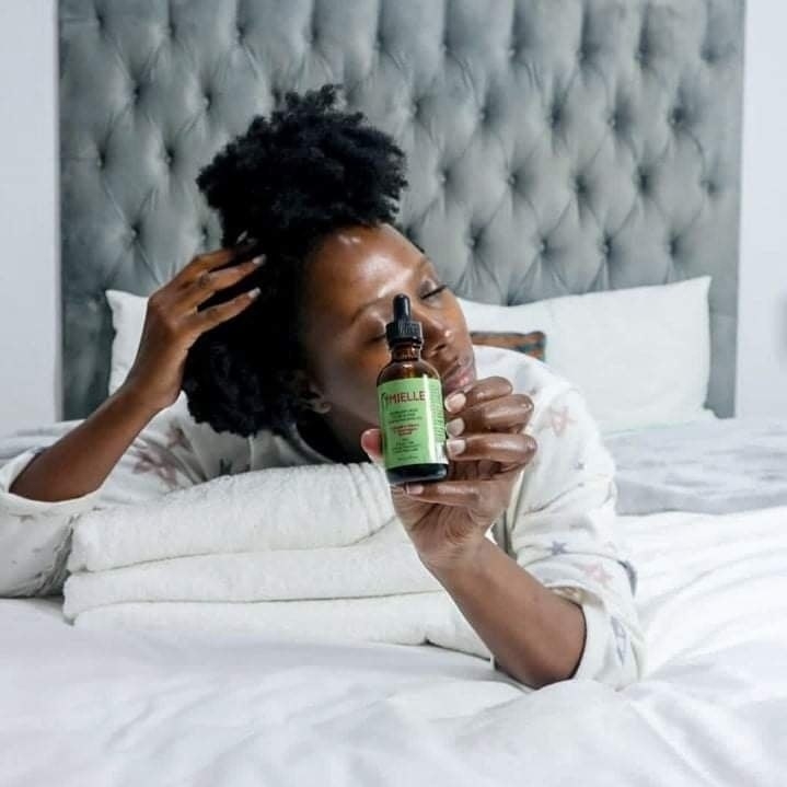 a person holding the scalp oil while lying in bed