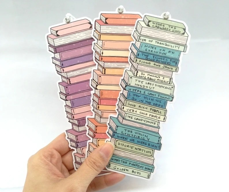 A person holding up three of the bookmarks in one hand