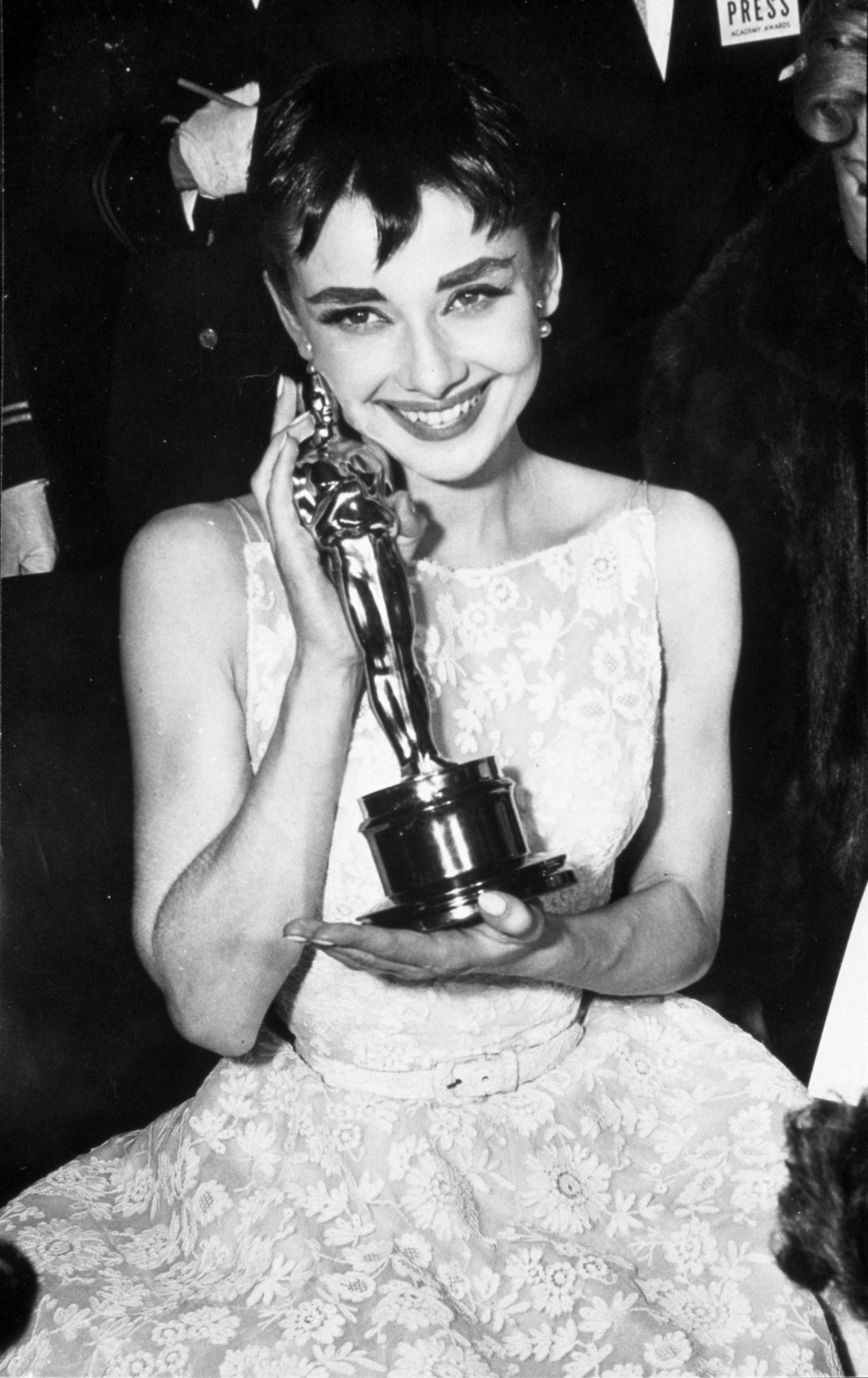 Audrey wearing a lacey white gown with a belt