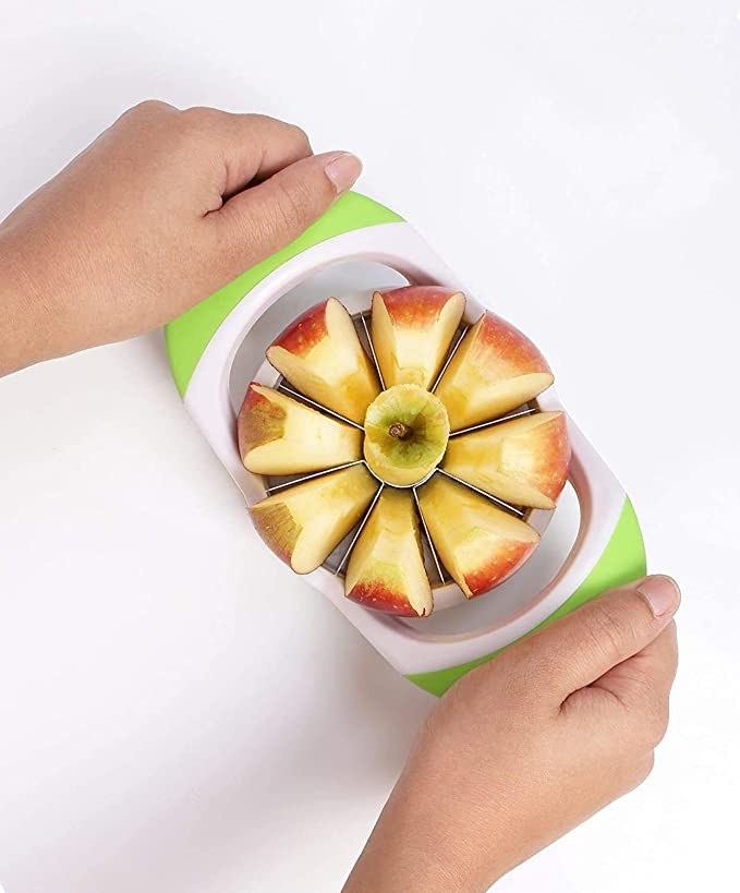A person pressing down on the apple slicer to cut up an apple