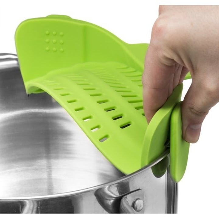 a hand clipping the bright green strainer onto a pot