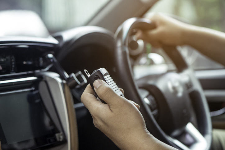 A person&#x27;s hand holding a wireless transmitter box inside a car