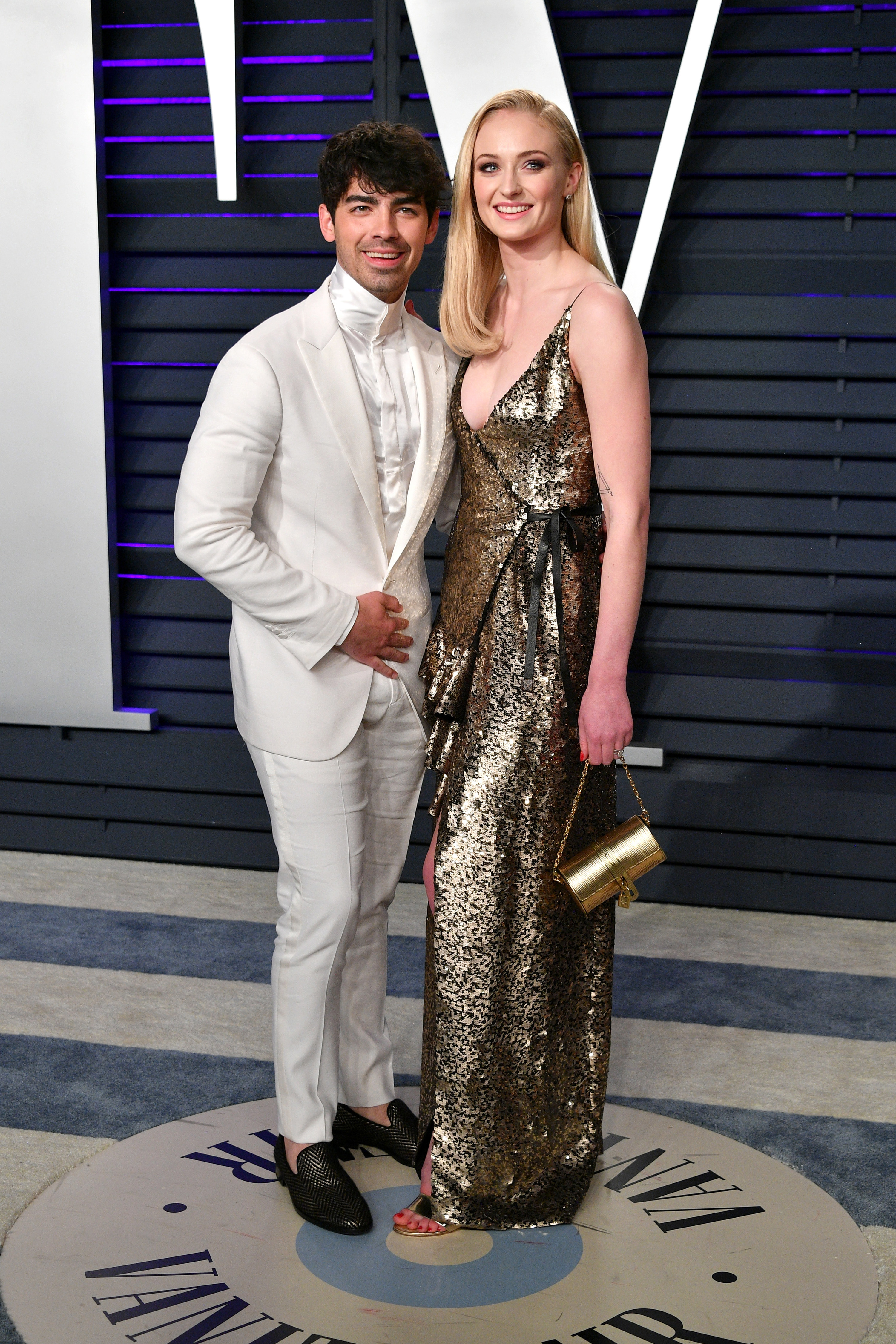 Joe wears a white suit and Sophie wears a shimmering gold gown