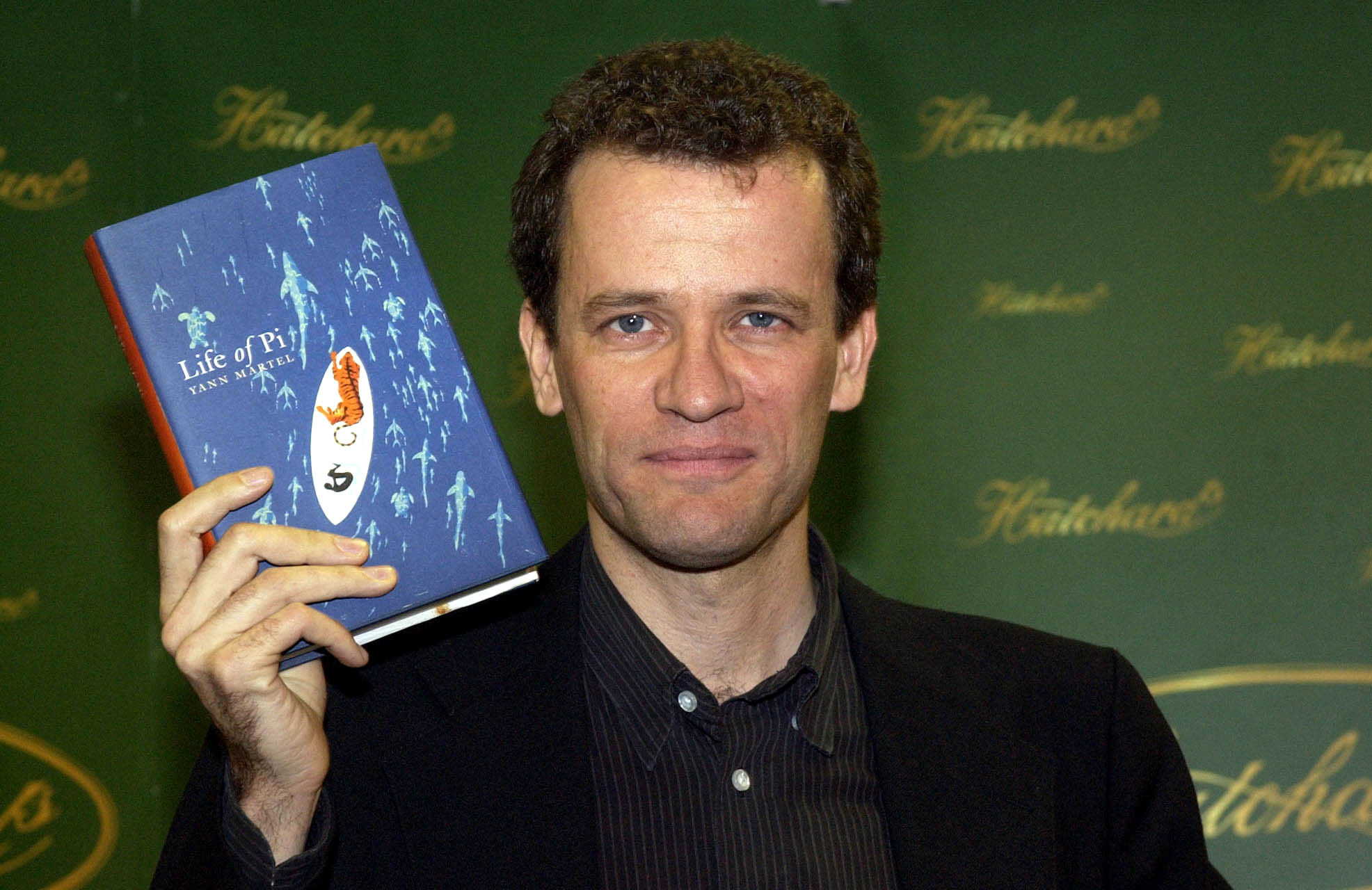 Yann Martel holding up a copy of his novel Life of Pi