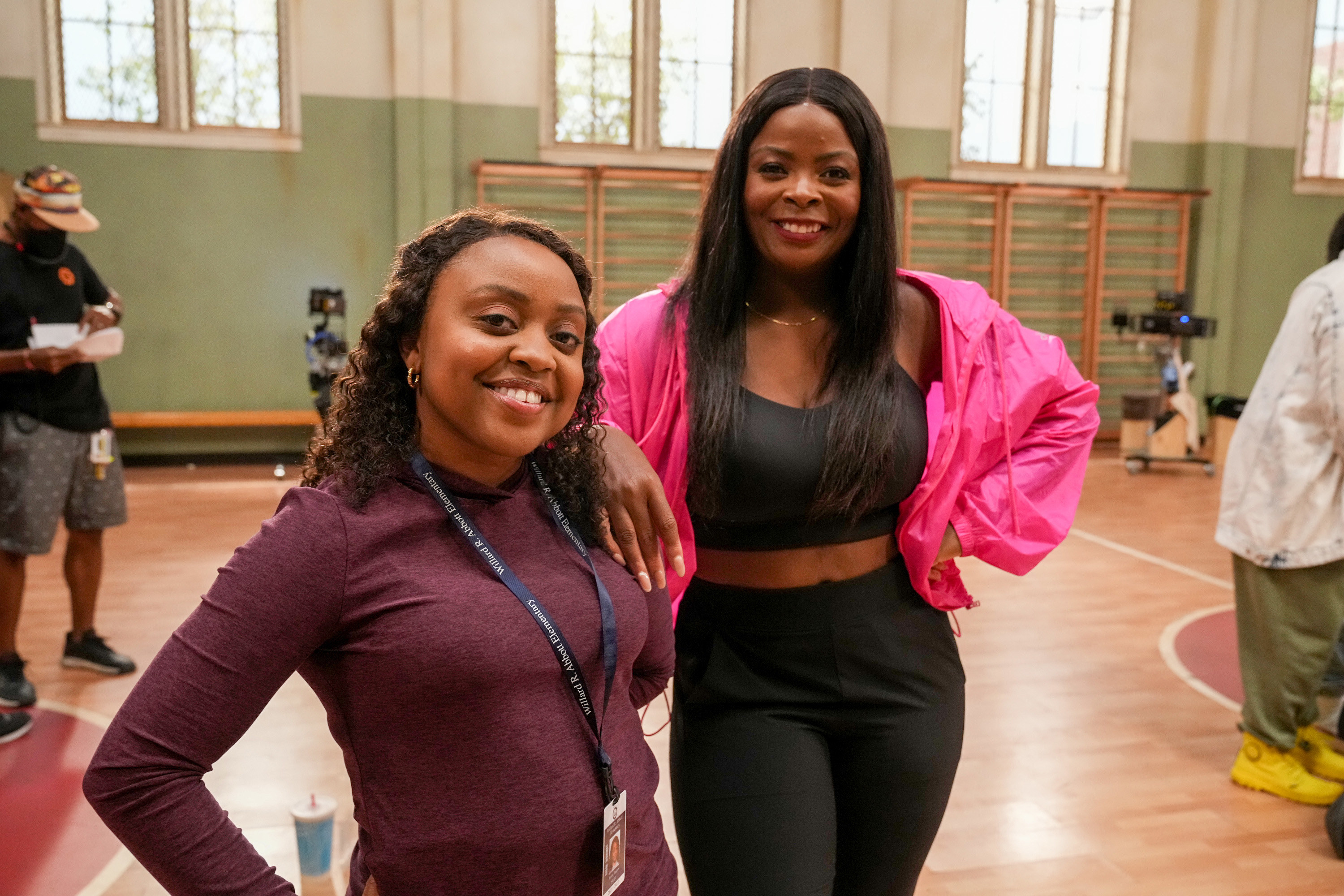 Quinta stands in a school gym with another teacher on the show&#x27;s set
