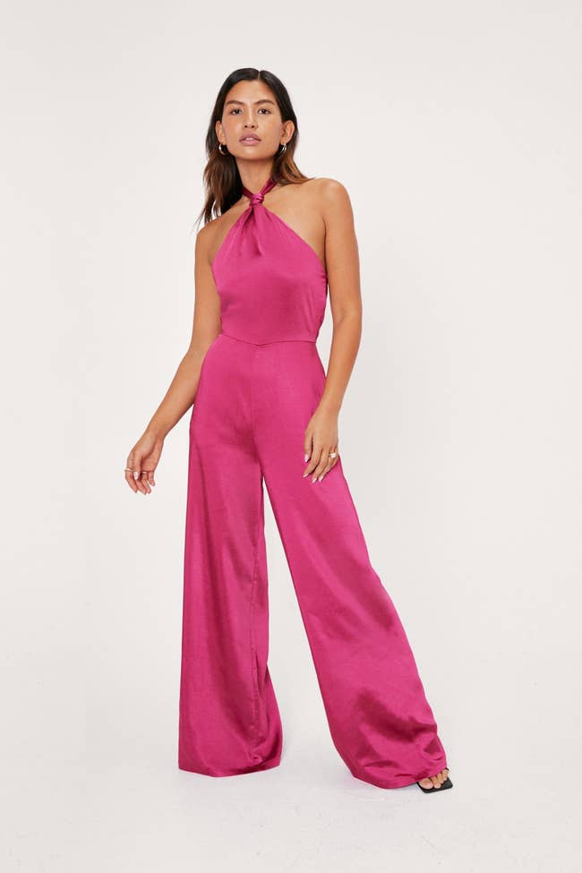 a model poses in a hot pink jumpsuit