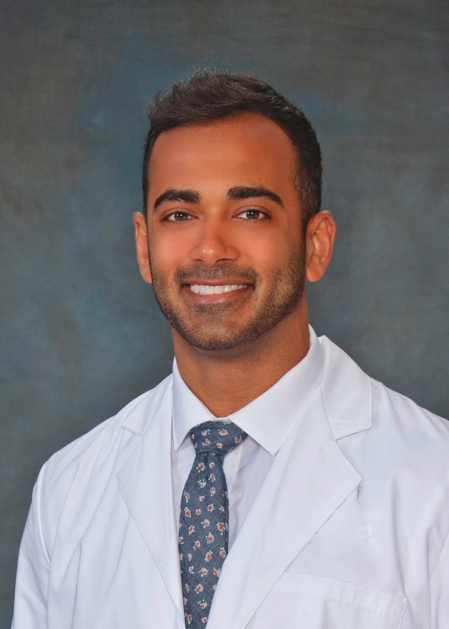 Dr. Sanjay Juneja for a portrait wearing a coat and tie