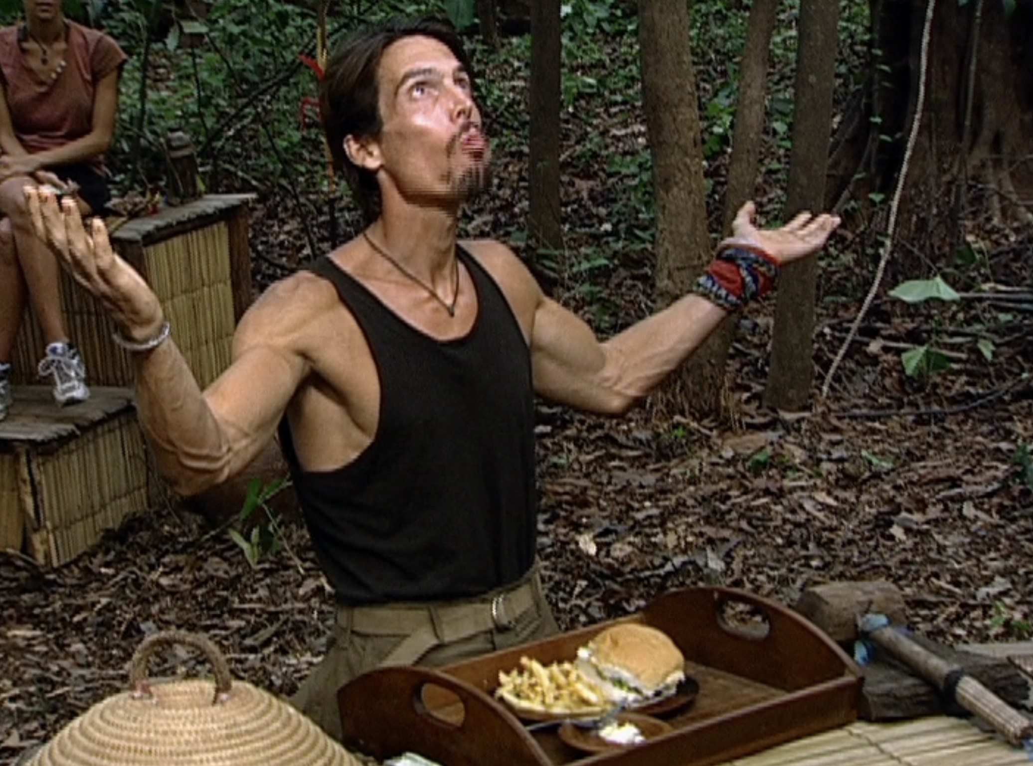 matthew in survivor the amazon with his arms stretched toward the sky after willing a cheeseburger at the aucution