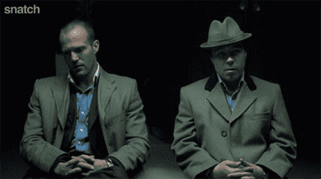 Jason Statham as Turkish and Stephen Graham as Tommy sitting looking sheepish in front of the camera