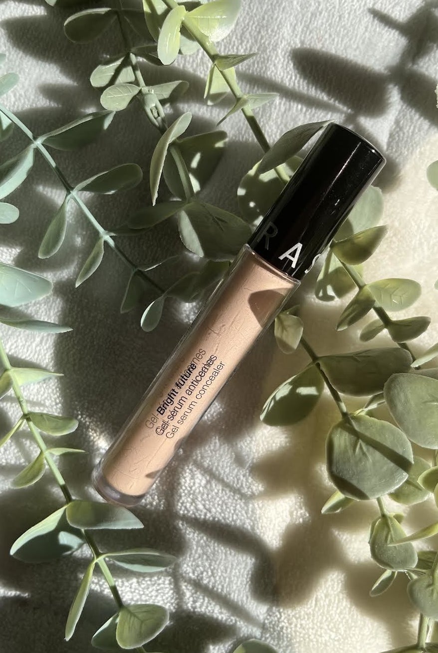 A  tube of concealer on a blanket surrounded by plants