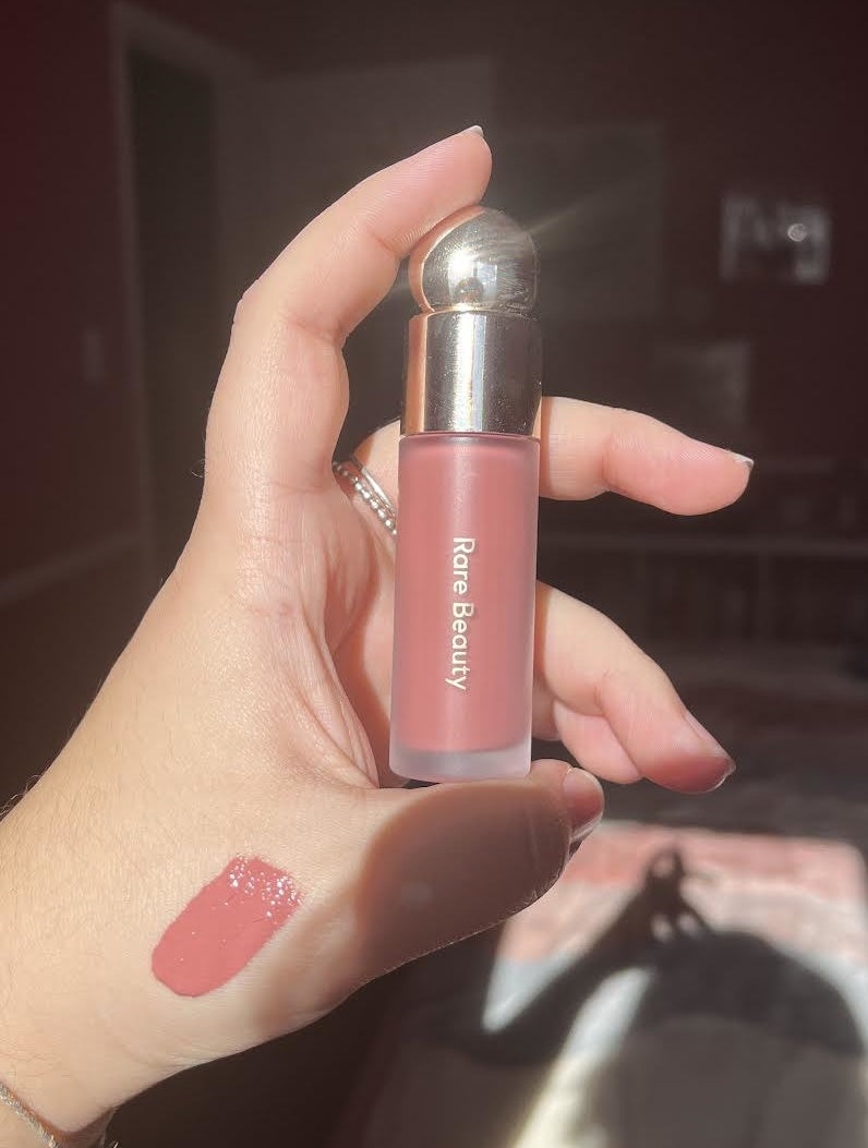 Bianca holding up a tube of the liquid blush with a swatch of it on the outside of her hand