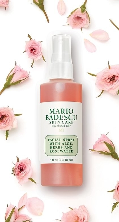 the rosewater facial spray bottle next to pink rose petals