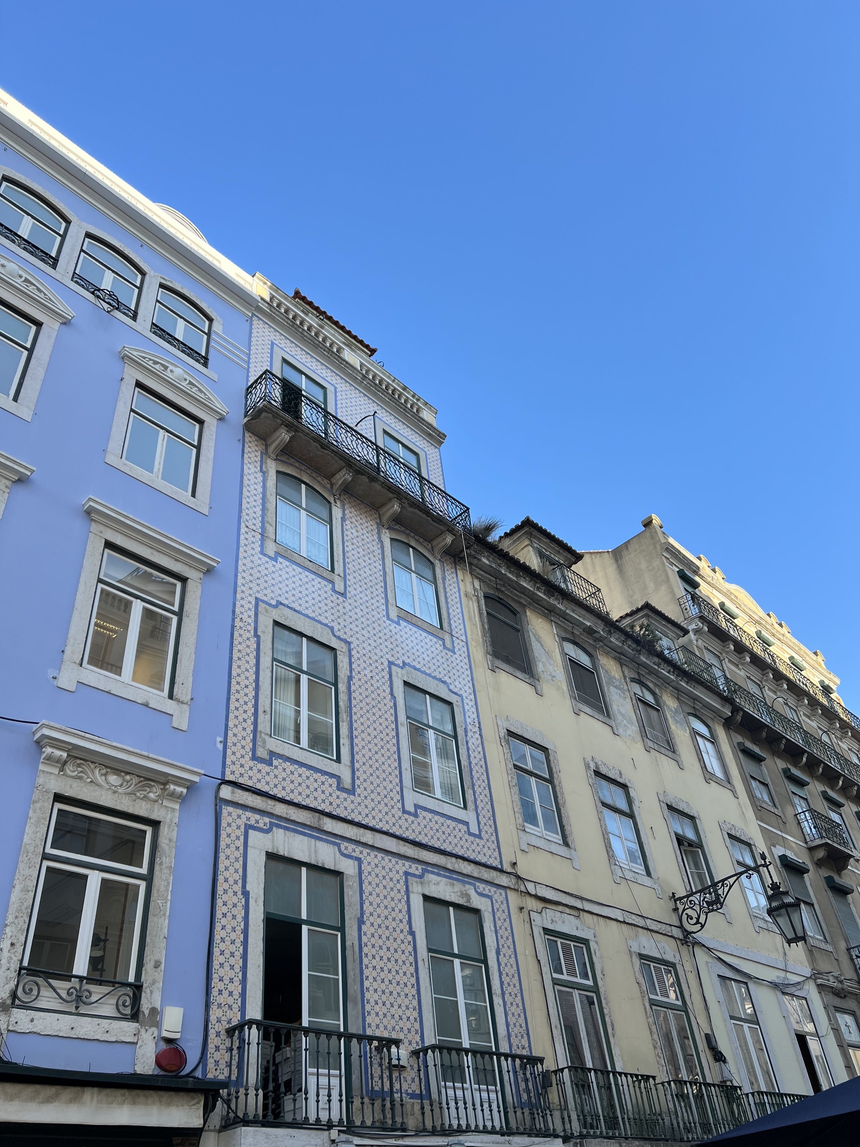 a street block in Lisbon with pastel colored buildings and tiles