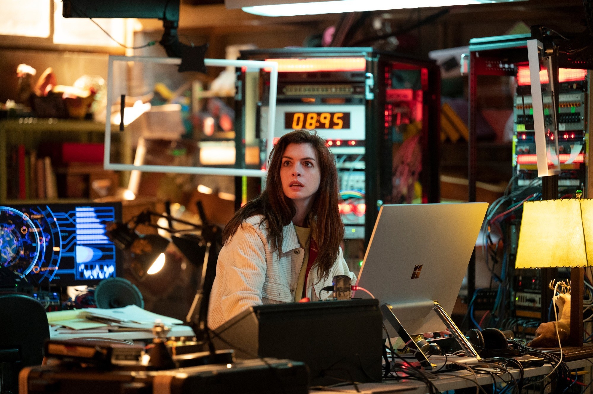 Anne Hathaway sits on a computer in a bunker