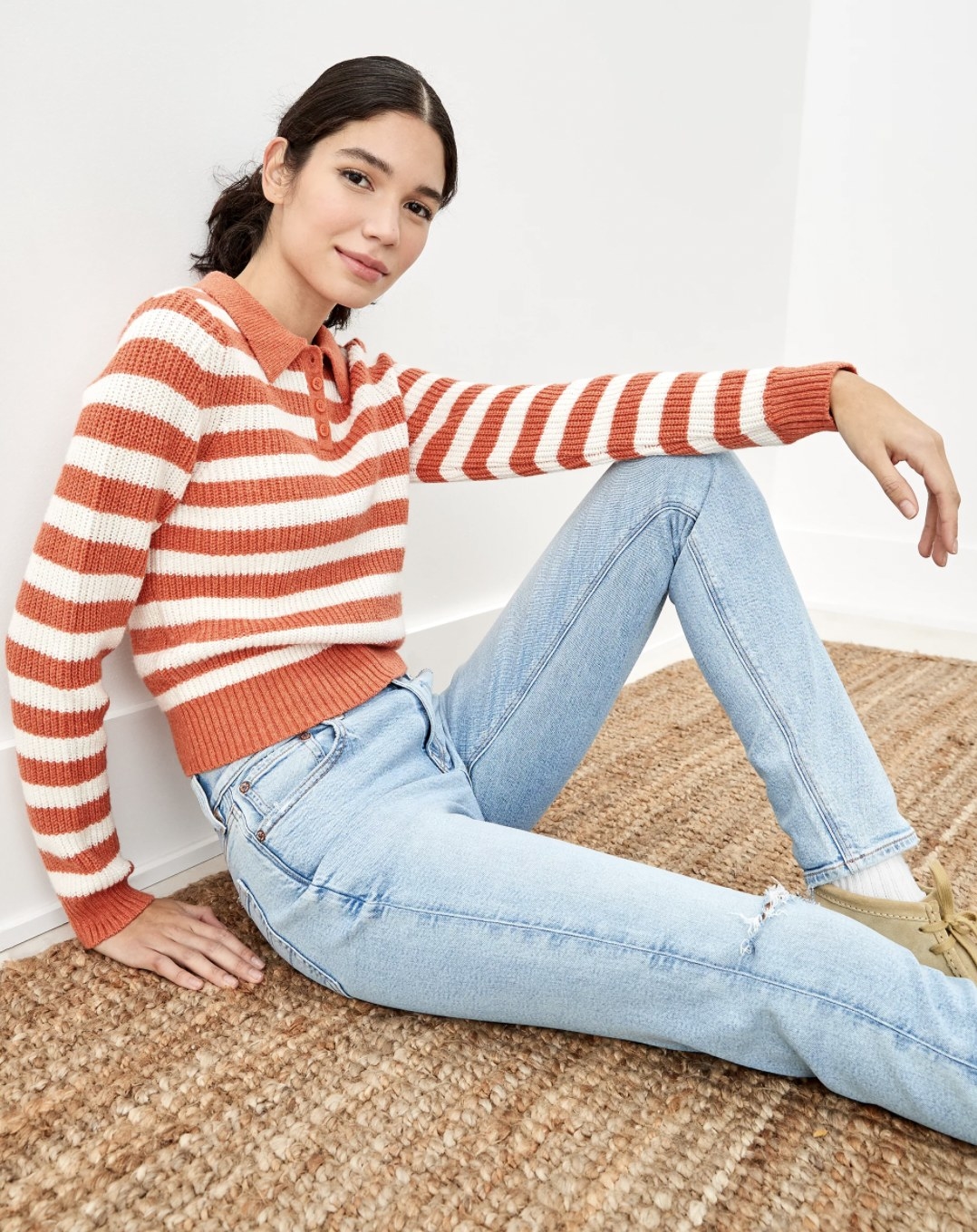 a model wearing the sweater in red and white stripes