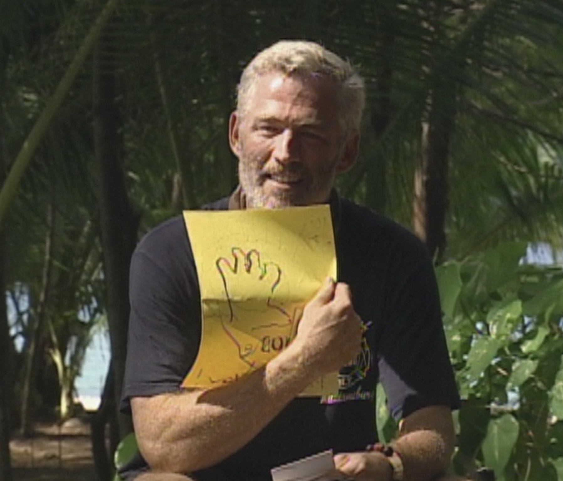 tom holding up a drawing done by his child on a yellow piece of paper