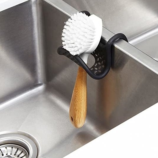 A sink caddy holding up a brush in an empty kitchen sink