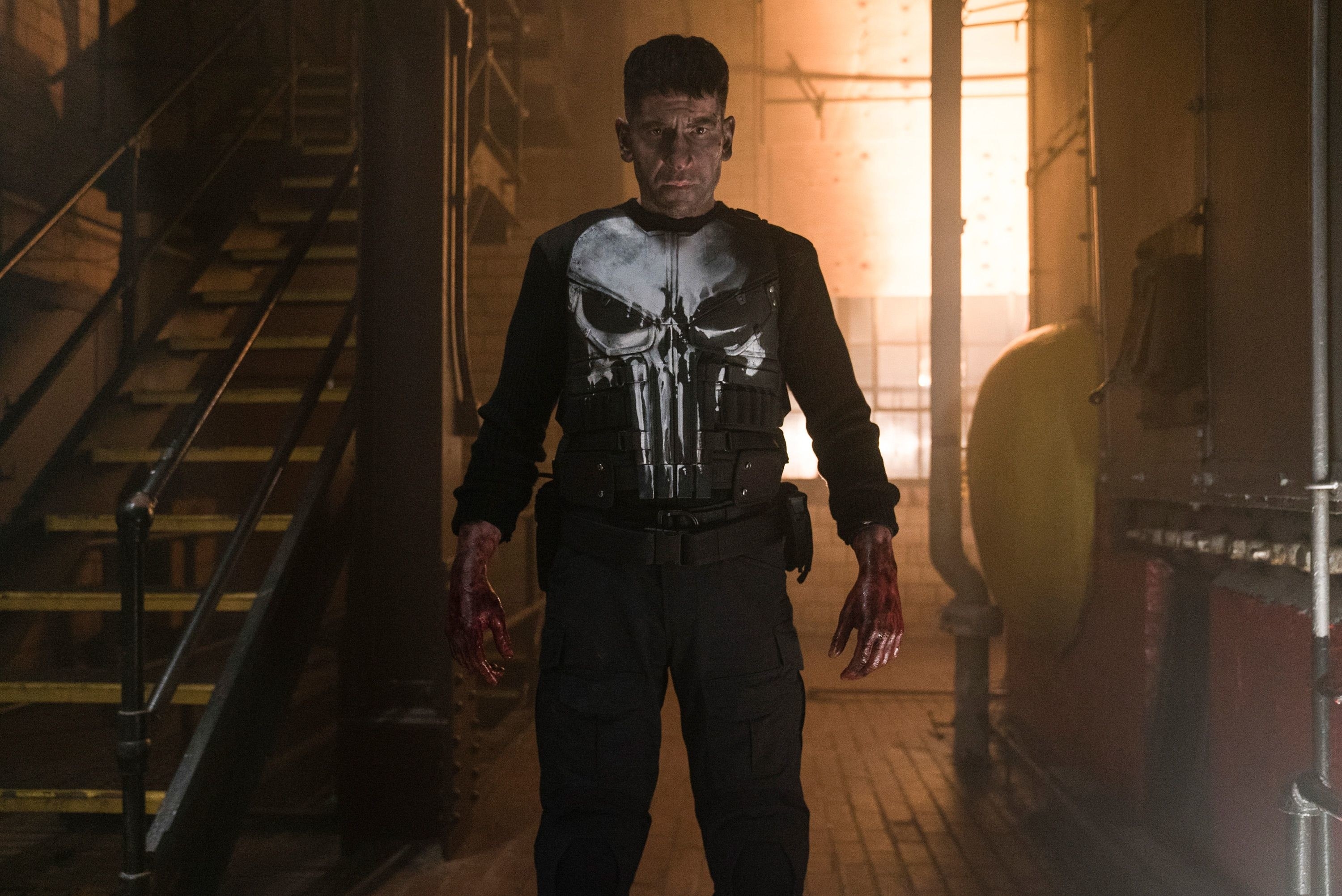 The Punisher standing next to some stairs, with blood on his hands