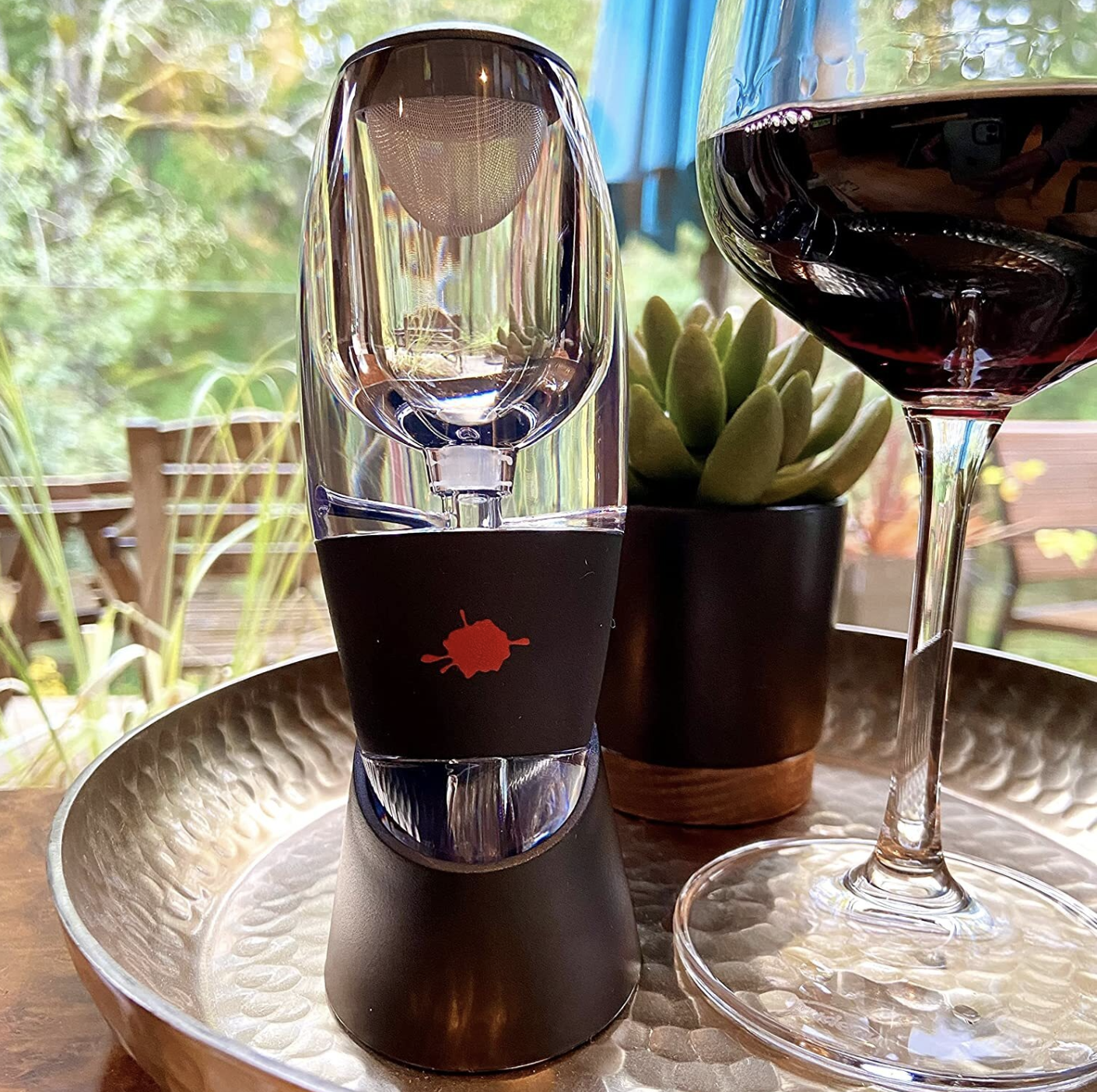 The wine decanter on it&#x27;s stand next to a glass of wine