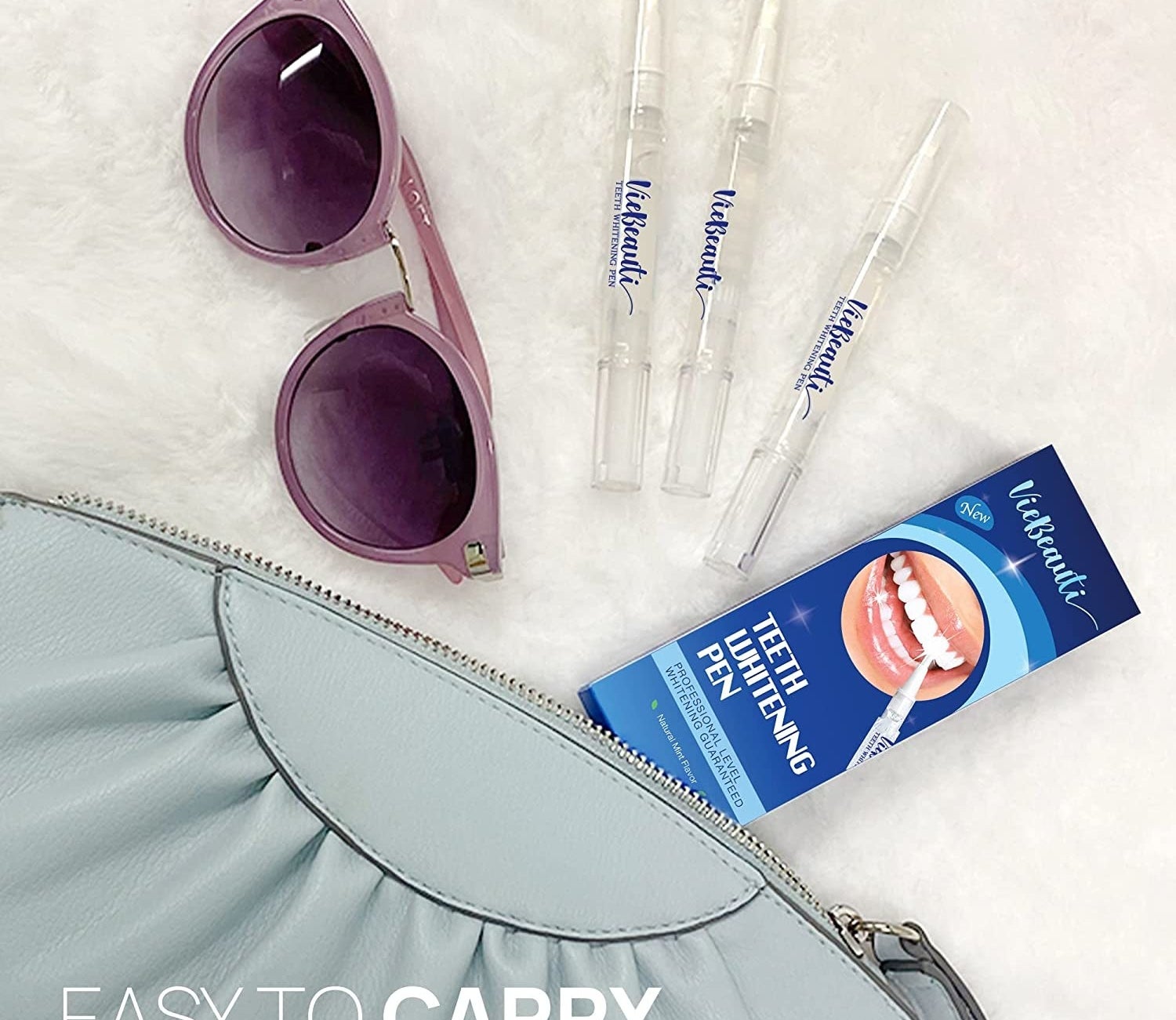 The pens surrounded by their box, sunglasses, and a purse