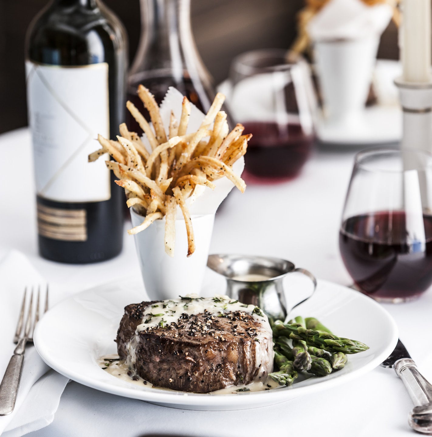 steak with sauce, fries, asparagus and wine