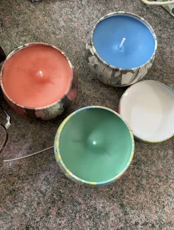 A reviewer's handmade candles in green, orange, and blue colors