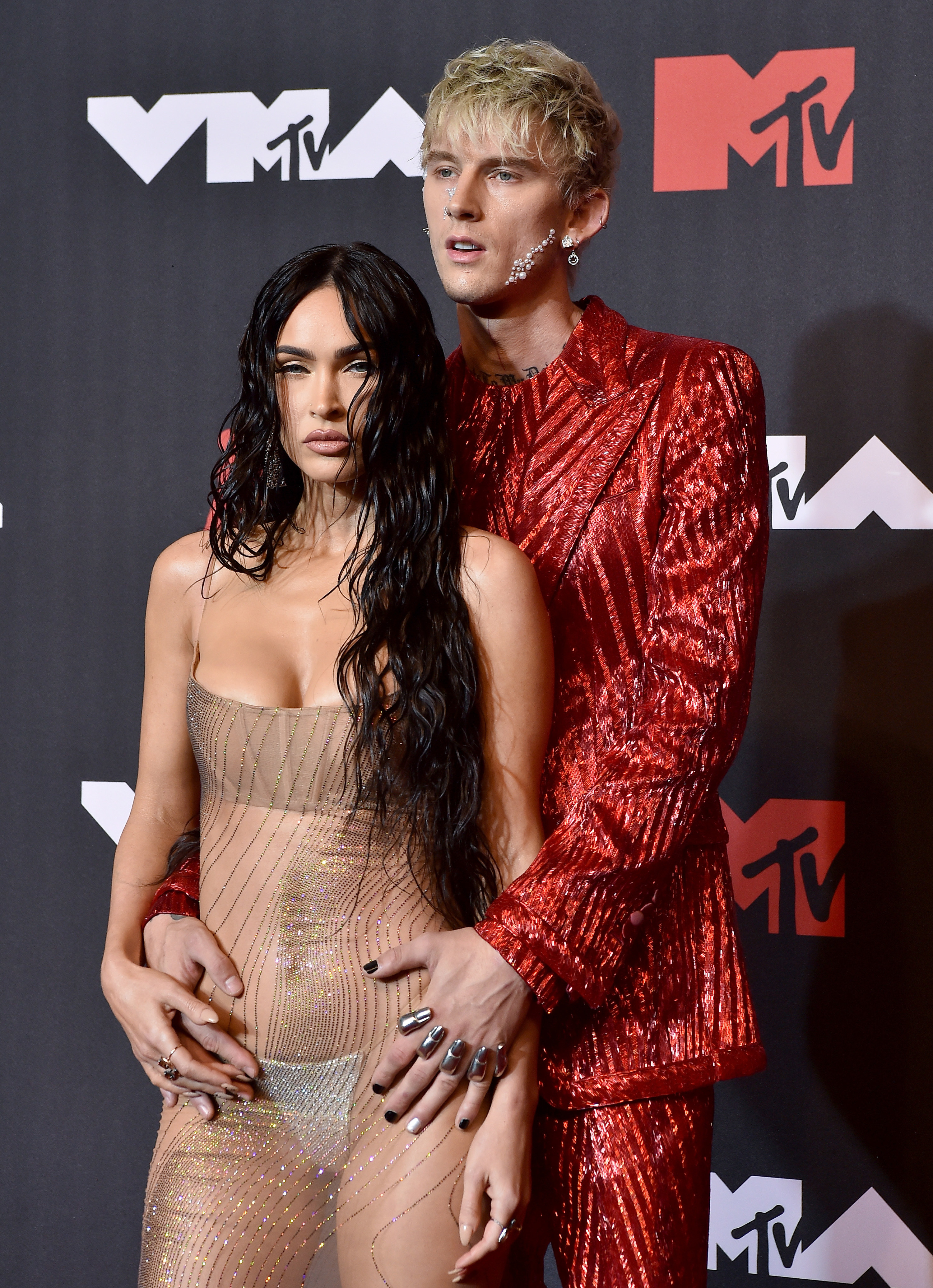 MGK stands behind Megan who wears a sheer dress for the MTV awards