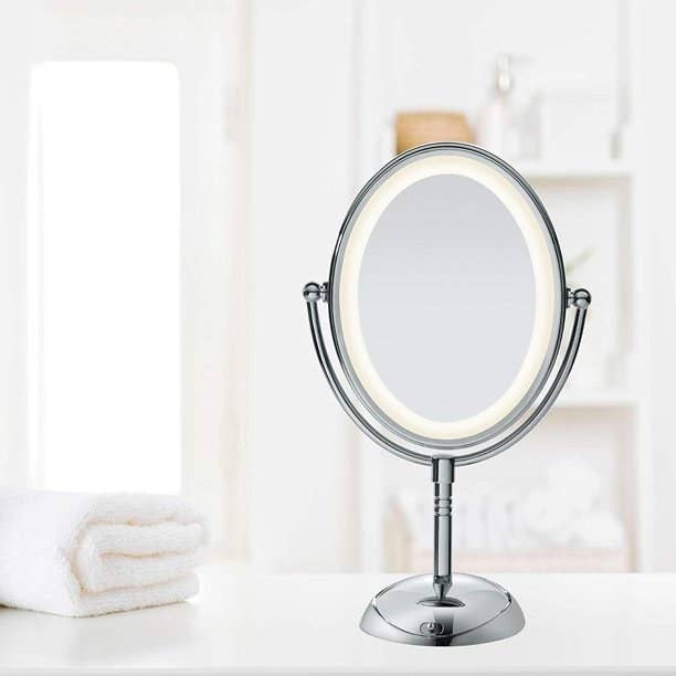 Oval shaped silver mirror with LED light border on bathroom counter