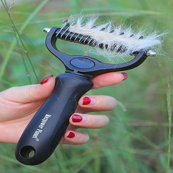Someone holding up the brush with a bunch of fur in it