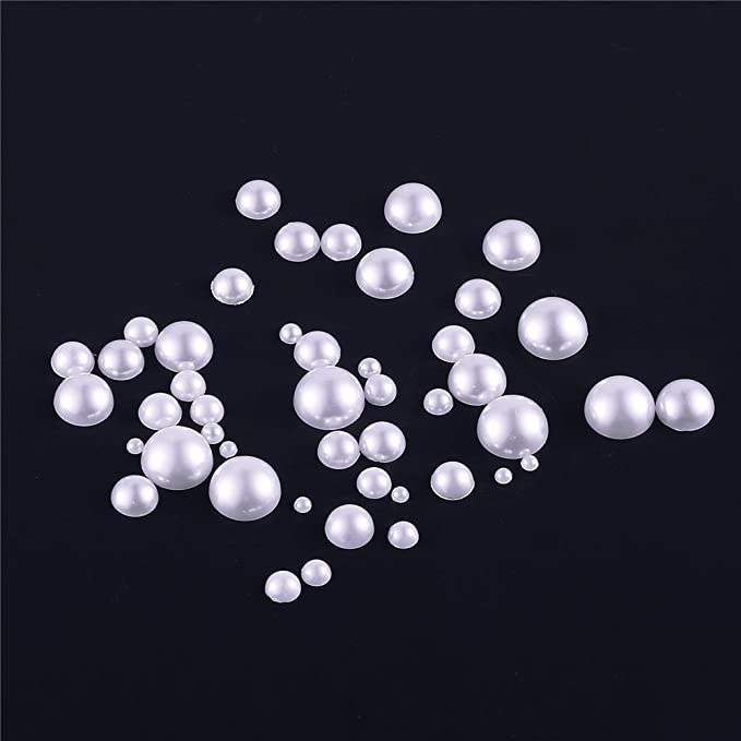 A group of the different sized half pearls scattered on a dark background