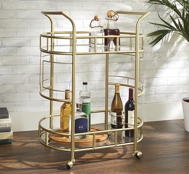 the gold bar cart with drinks on it