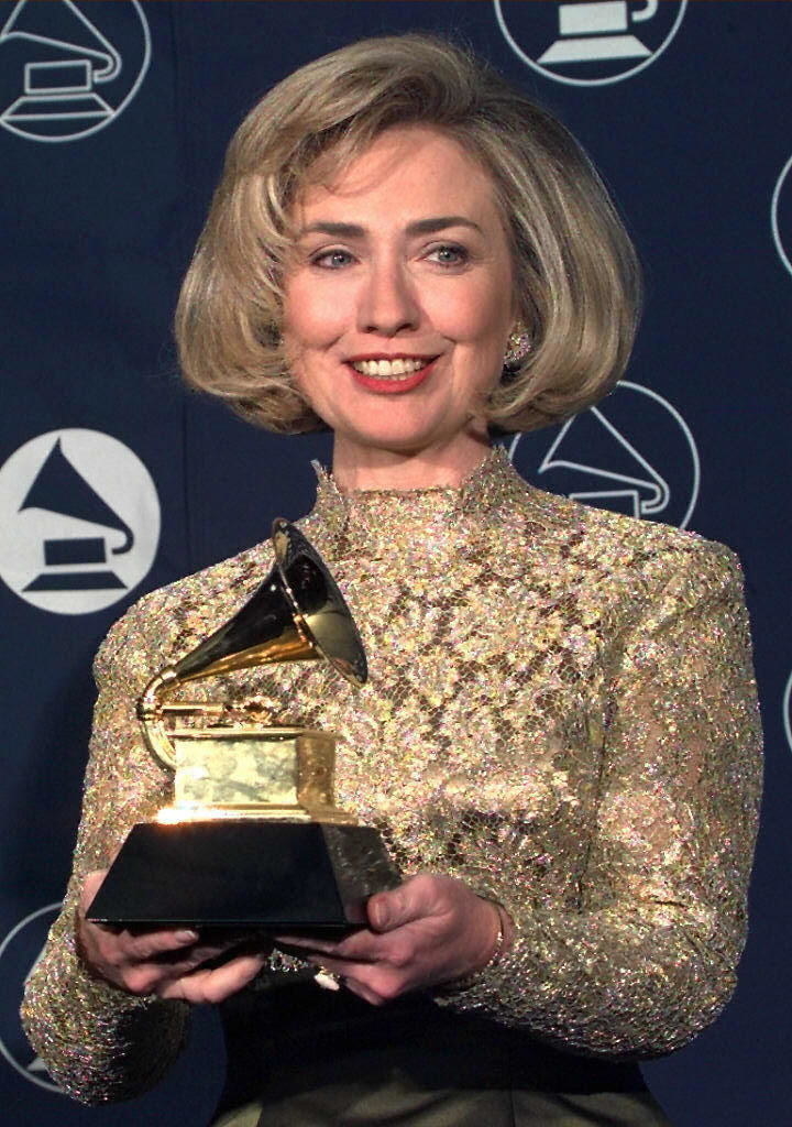 Hilary in the &#x27;90s wearing a lace long-sleeved dress while holding her award