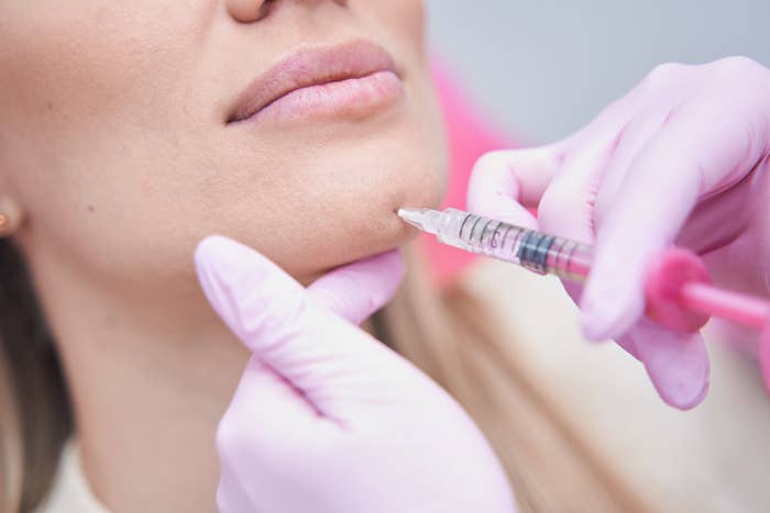 Cropped photo of an experienced doctor injecting dermal filler into the chin of a female patient