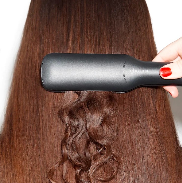 Model straightening hair with flat iron