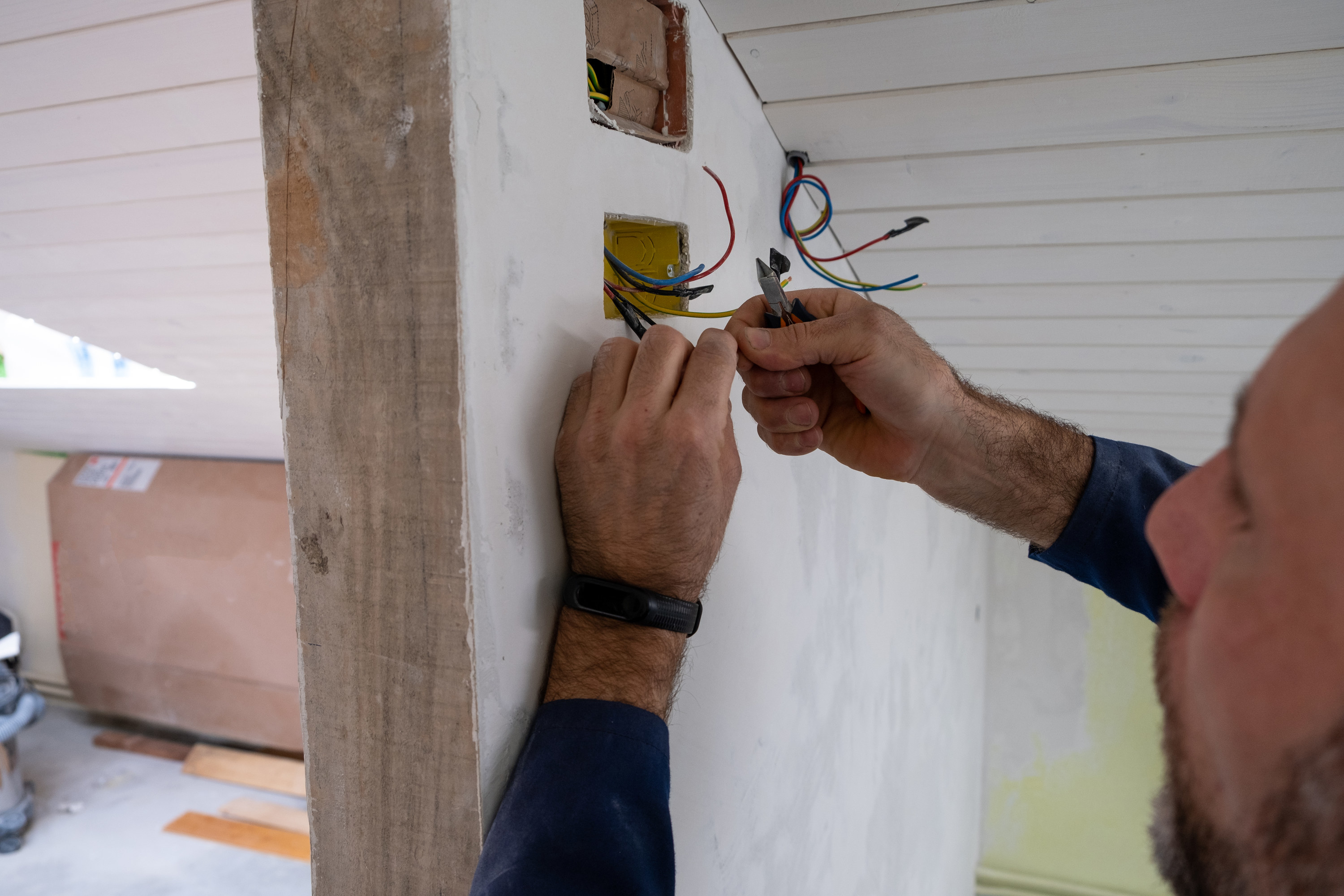 a man working on wires that are sticking out from the wall