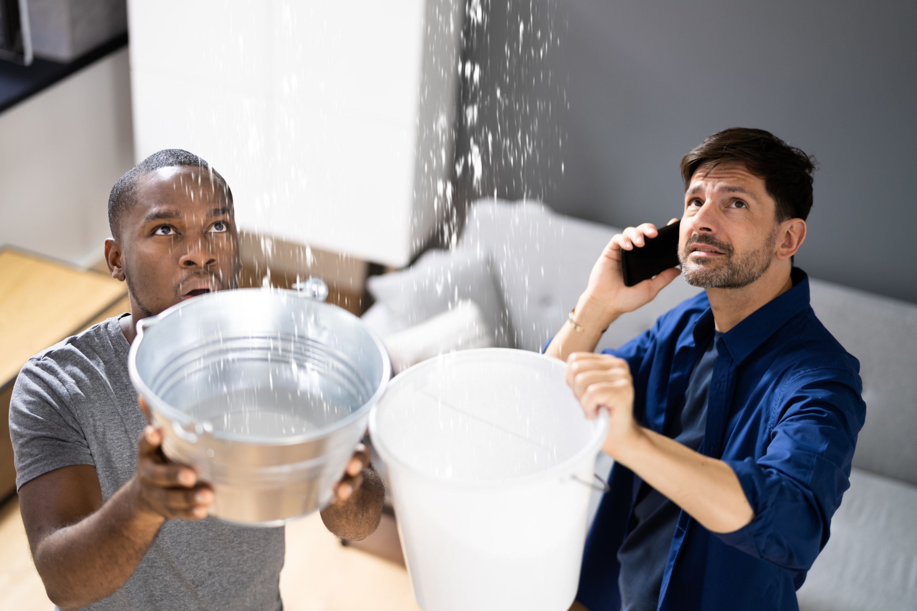 two people catching water from the rood in large buckets