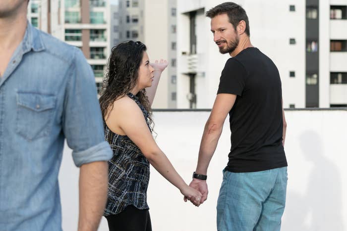 A guy checks out another man while holding his girlfriend&#x27;s hand