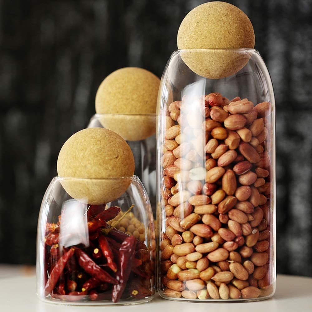 a trio of glass canisters with cork ball tops