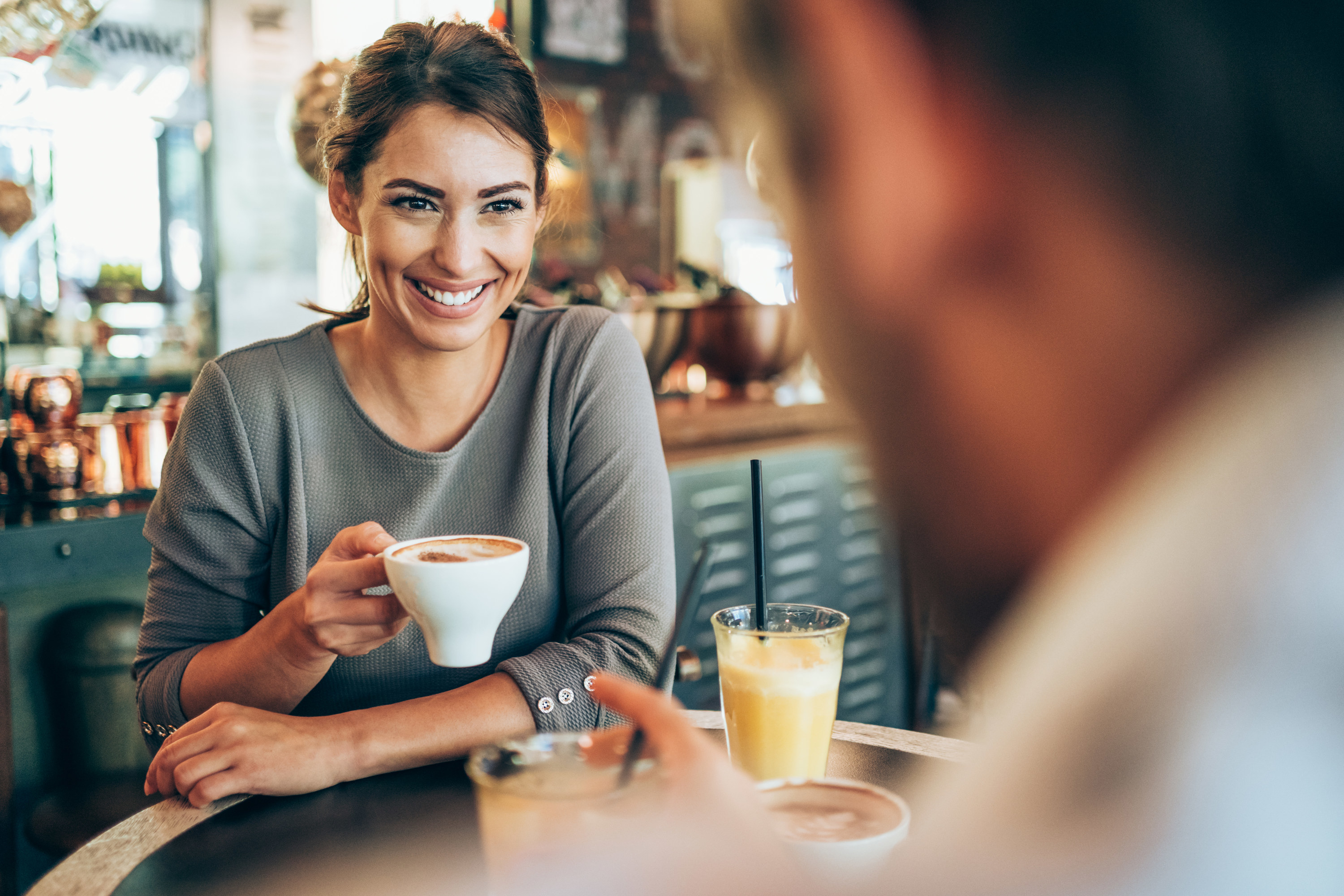 a woman holding a coffee mug smiling at the person across from her
