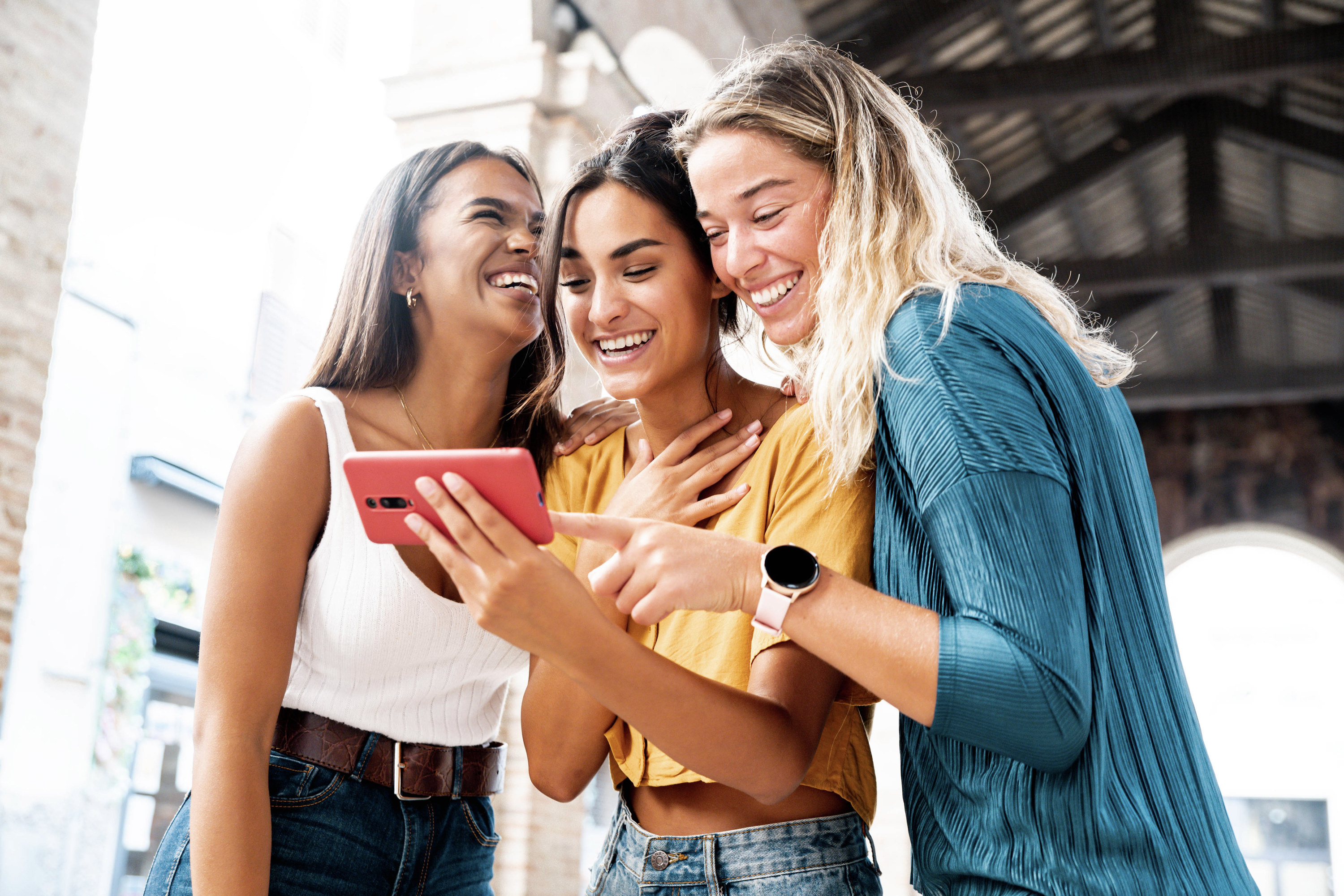 three female friends smiling and looking at a phone together