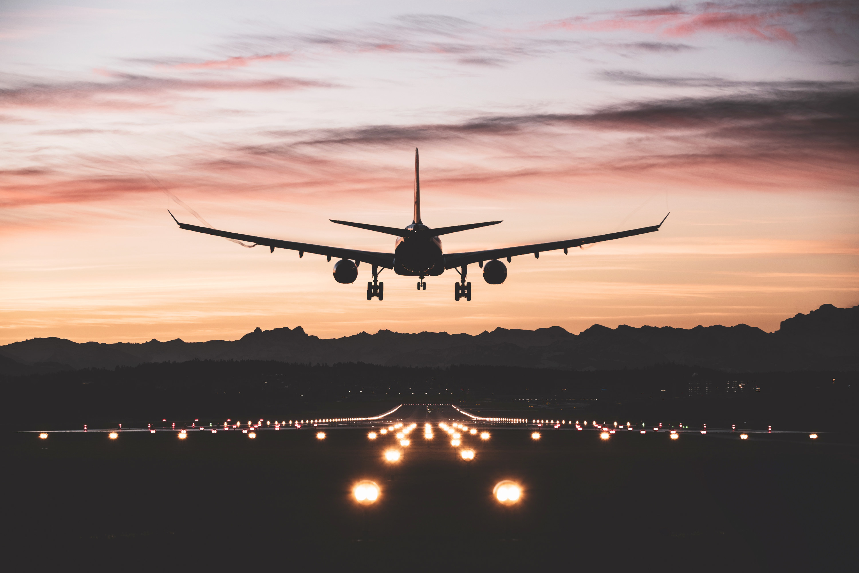 an airplane landing on a runway at sunset