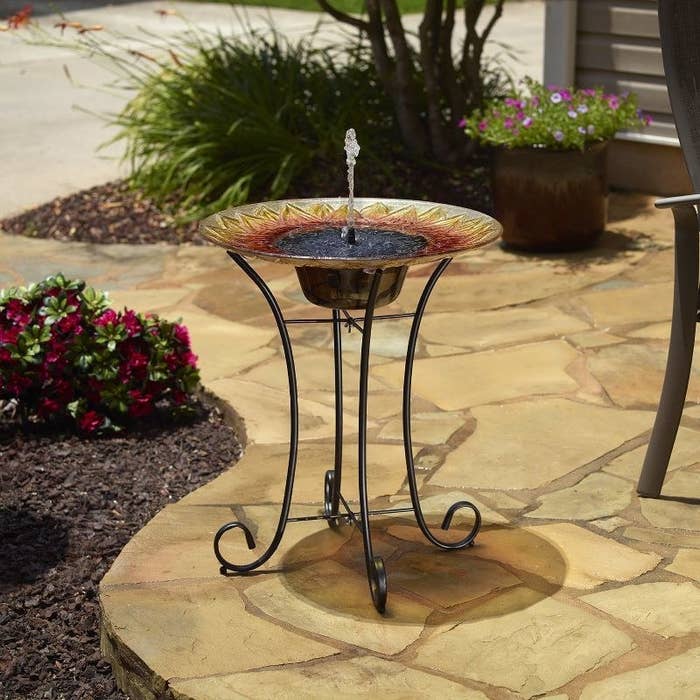 the sunflower pedestal bird bath on patio with water bubbling from top