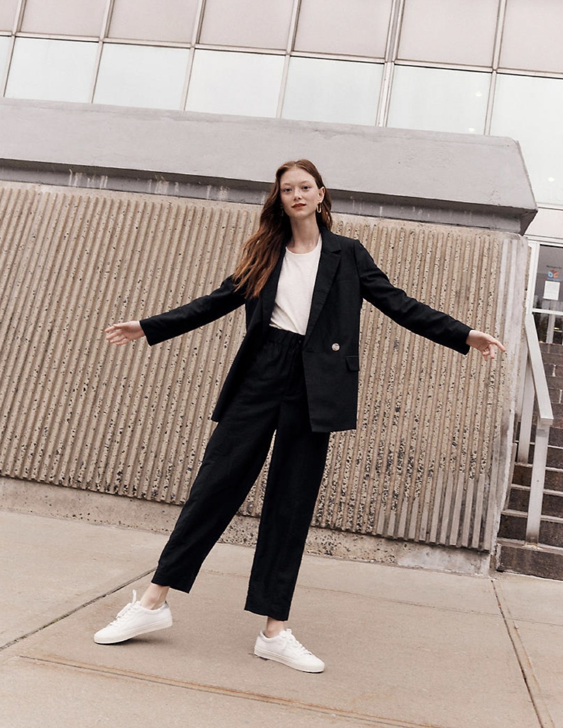 Model wearing the blazer over white tank with black trousers and white sneakers