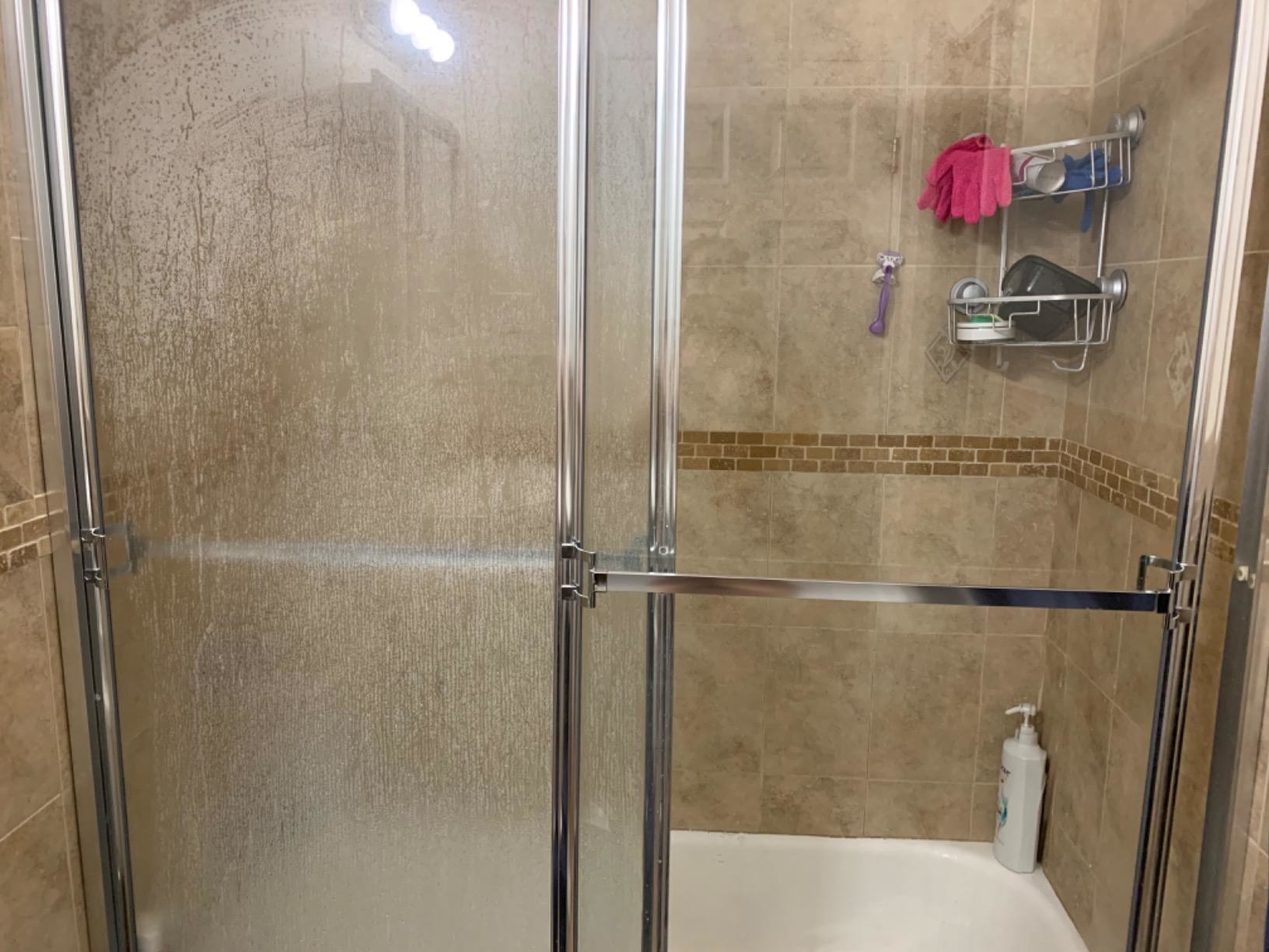 Reviewer image of stained shower door vs clean shower door