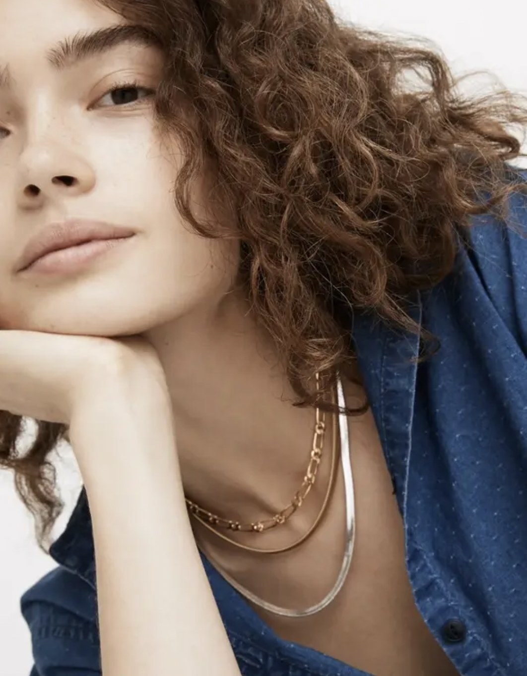 Model wearing the gold and silver chain layered with gold paperclip necklace