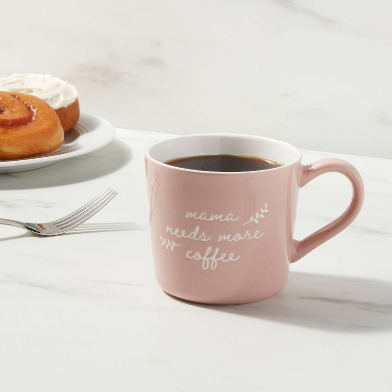 The pink mug with message in white cursive font filled with coffee